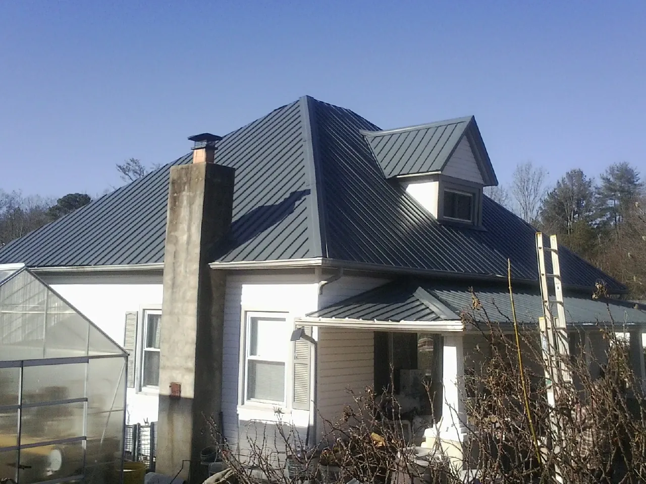 Dark blue standing seam metal roof on a white farmhouse with dormer — Slate & Tile Roof Repair by Roofing Brothers in Bretton Woods