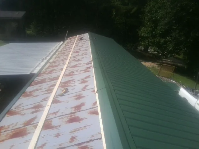 Old rusted panels beside newly installed green metal roofing — Wind Damage Roof Repair by Roofing Brothers in Bretton Woods