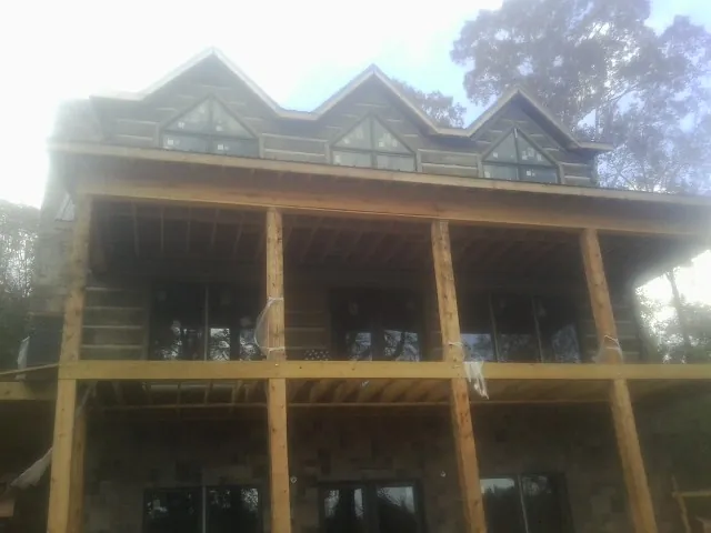 Dormers and porch framing on a large log home under construction — Roof Coating work by our crew in Bretton Woods