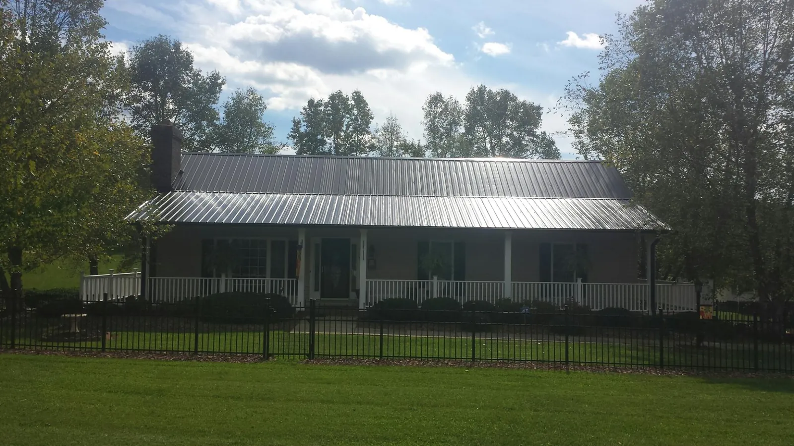 Gray metal roof on a brick ranch with a full width front porch — Gutter Guard Installation work by our crew in Bretton Woods