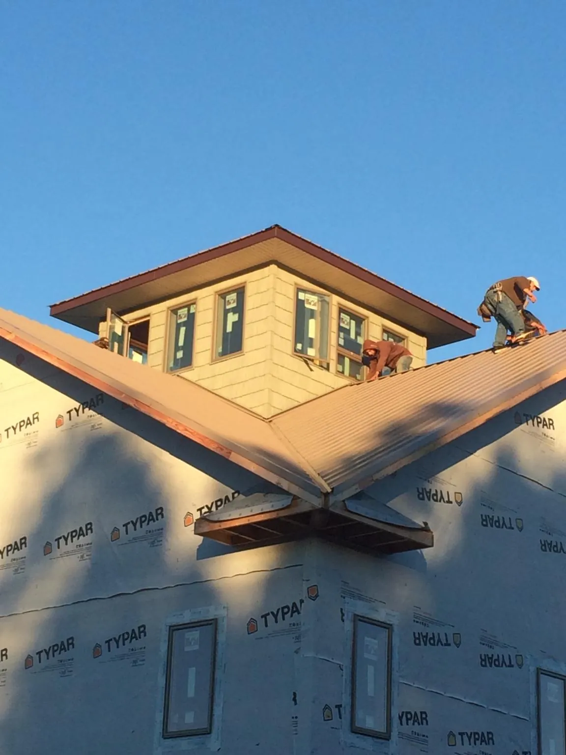 Roofers working around a rooftop cupola on a new metal roof at sunset — Roof Waterproofing in Bretton Woods by Roofing Brothers